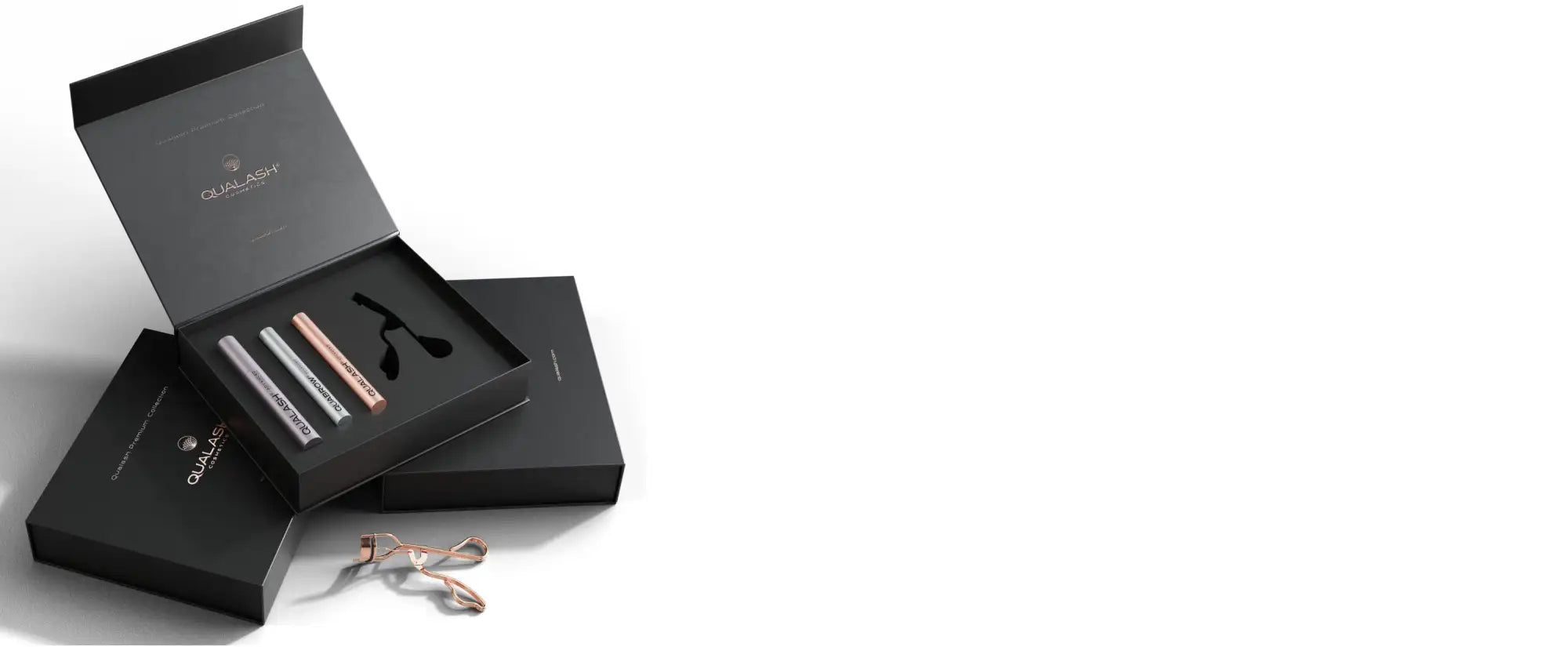Black luxury box containing three sleek, metallic eyelash curlers in silver and rose gold finishes.