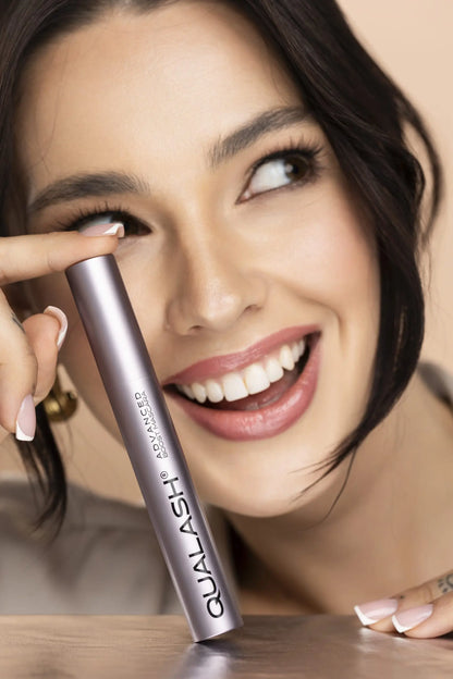 Woman applying QUALASH Advanced Mascara Volume Max to upper lashes using precision brush – Step 1